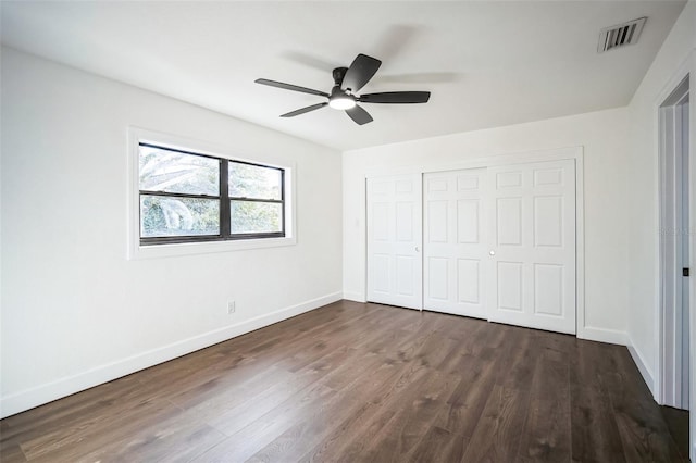 unfurnished bedroom with visible vents, ceiling fan, baseboards, a closet, and dark wood-style floors