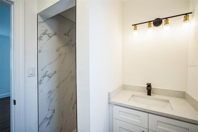 bathroom with vanity and a marble finish shower