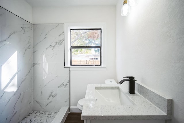 full bathroom with a marble finish shower, toilet, and vanity