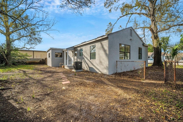 back of property featuring stucco siding, central AC, and fence