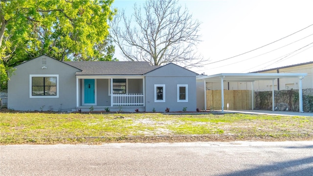 view of front facade featuring stucco siding, driveway, a porch, and a front yard