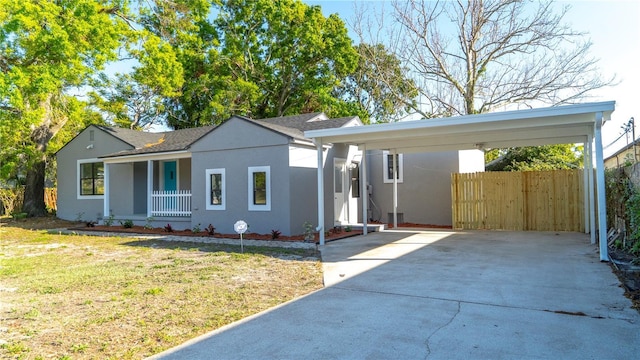 single story home featuring a front lawn, fence, concrete driveway, stucco siding, and a carport