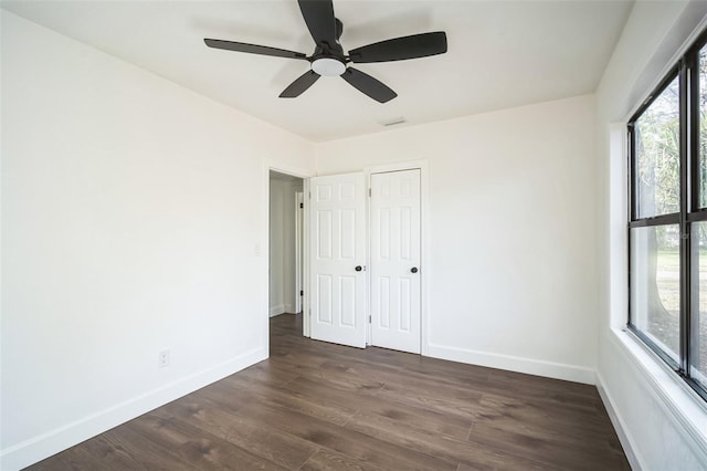 unfurnished bedroom featuring a closet, dark wood-style flooring, baseboards, and a ceiling fan