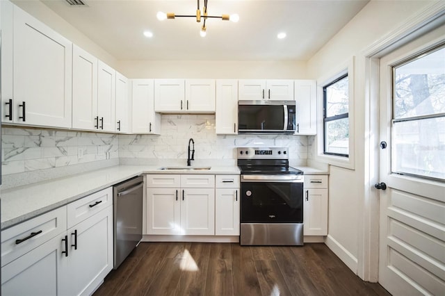 kitchen featuring white cabinets, appliances with stainless steel finishes, dark wood-style flooring, light countertops, and a sink