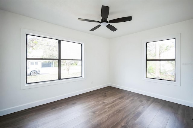 unfurnished room featuring dark wood finished floors, baseboards, ceiling fan, and a healthy amount of sunlight