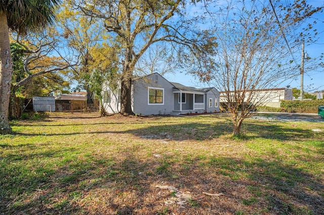 view of front of home with stucco siding, fence, and a front lawn