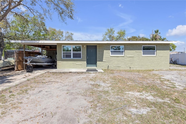 view of front of home with stone siding, an attached carport, driveway, and fence