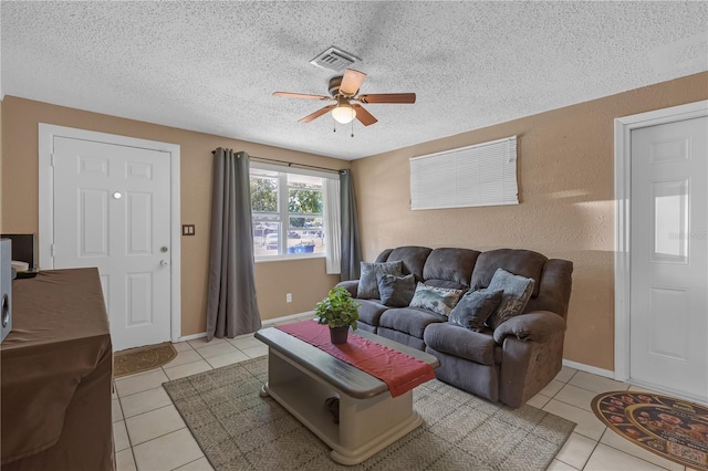 living area with a textured ceiling, light tile patterned flooring, visible vents, and ceiling fan