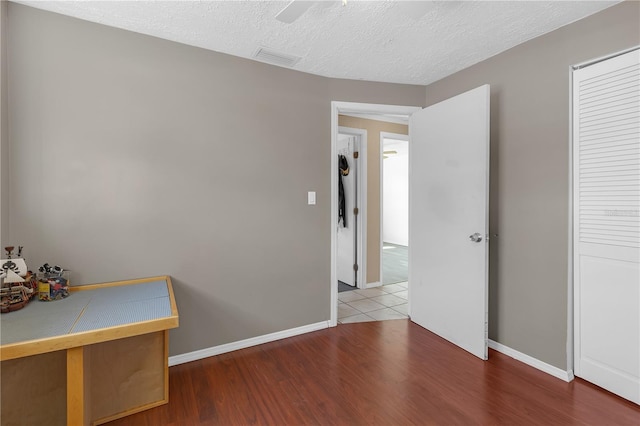 spare room featuring visible vents, a textured ceiling, baseboards, and wood finished floors