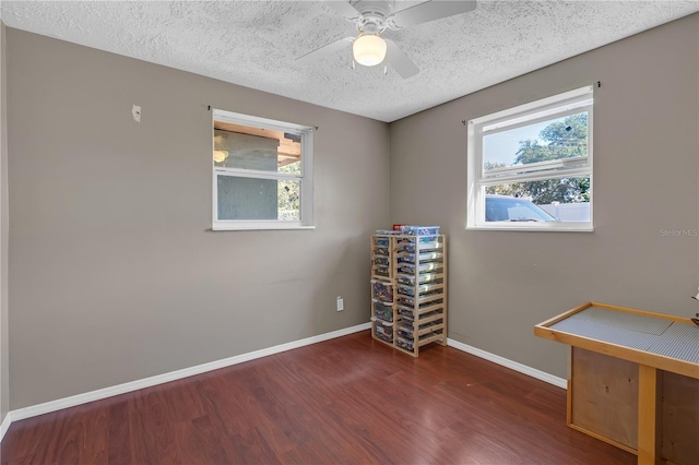 spare room with baseboards, a textured ceiling, wood finished floors, and a ceiling fan