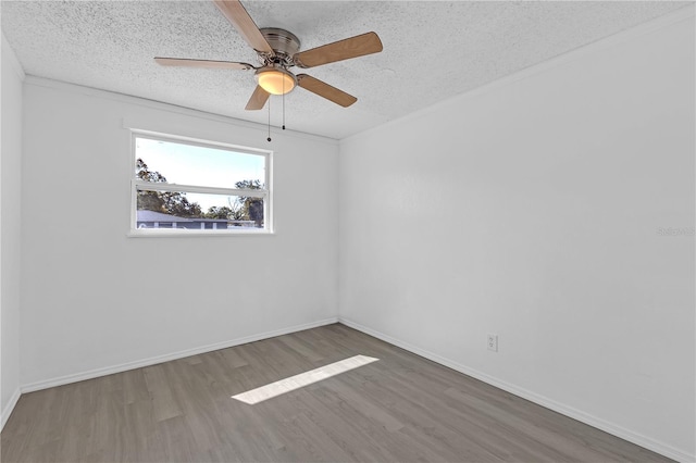 empty room with baseboards, a textured ceiling, and wood finished floors