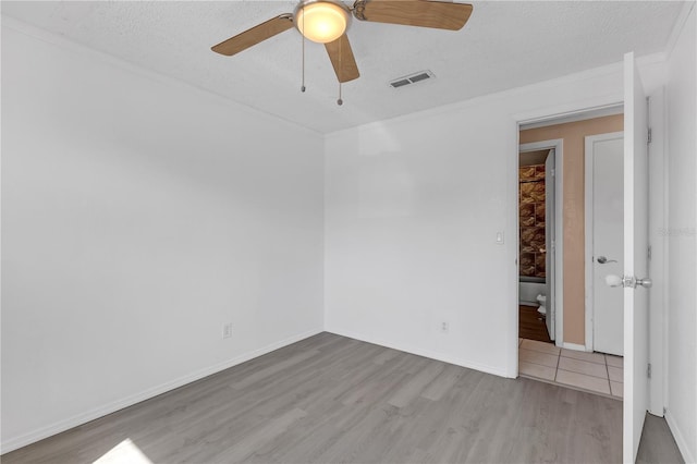 empty room featuring visible vents, baseboards, wood finished floors, a textured ceiling, and a ceiling fan