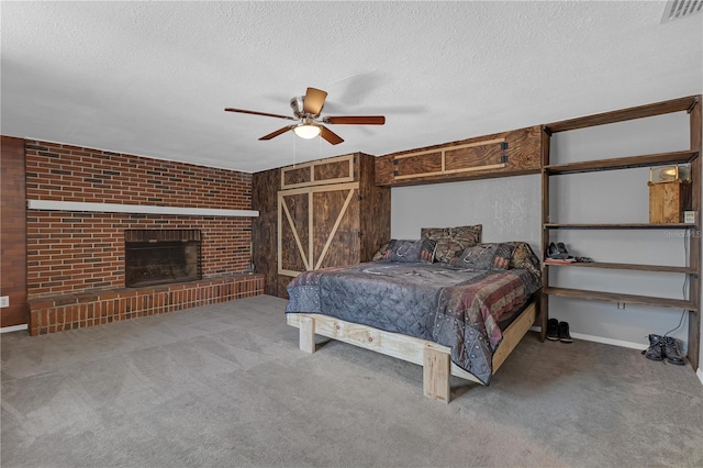 carpeted bedroom with ceiling fan, a brick fireplace, visible vents, and a textured ceiling