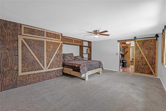 bedroom featuring a barn door, a ceiling fan, and carpet flooring