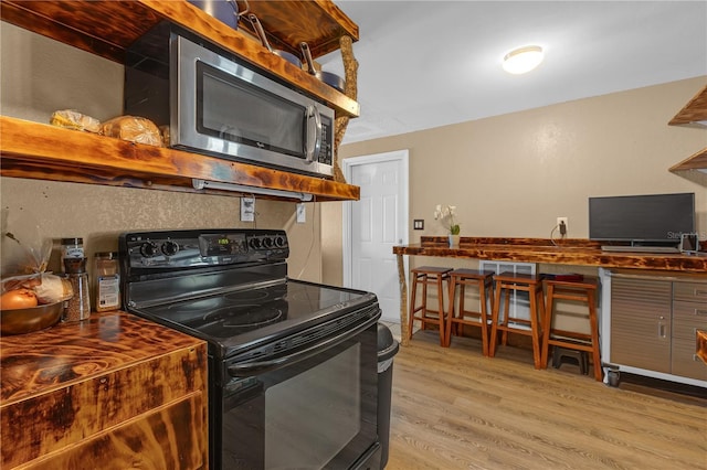 kitchen with stainless steel microwave, light wood-style floors, and black electric range oven