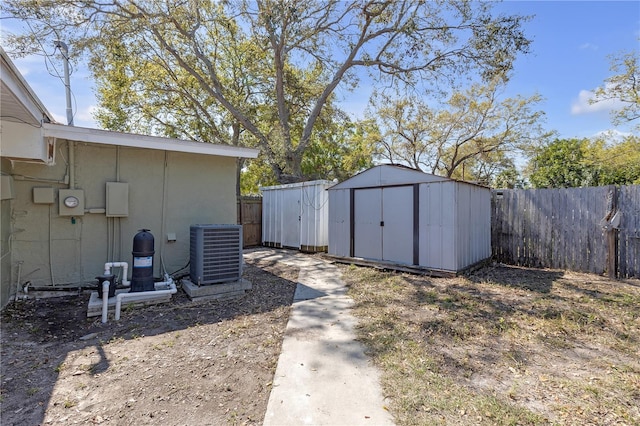 view of yard with central air condition unit, an outbuilding, a storage shed, and a fenced backyard