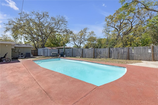 view of swimming pool featuring central AC, a storage shed, a fenced backyard, a patio area, and an outbuilding