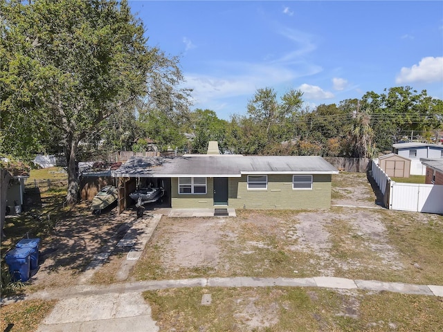 single story home with a carport, driveway, and fence