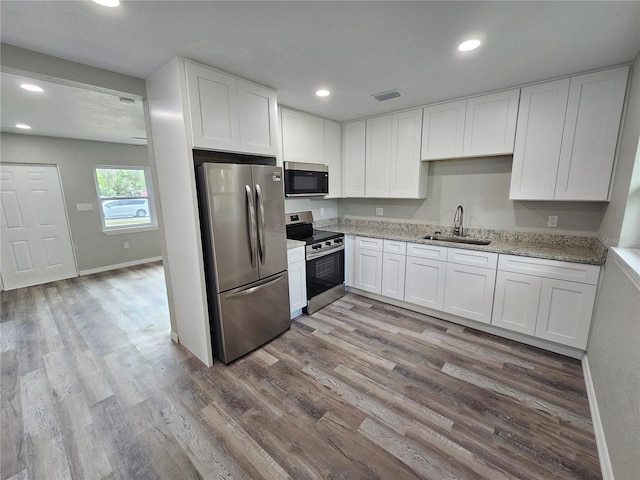 kitchen featuring white cabinetry, wood finished floors, appliances with stainless steel finishes, and a sink