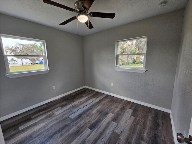 empty room featuring dark wood-style floors, a textured ceiling, and baseboards