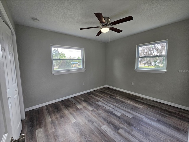 unfurnished bedroom with dark wood finished floors, ceiling fan, a textured ceiling, and baseboards