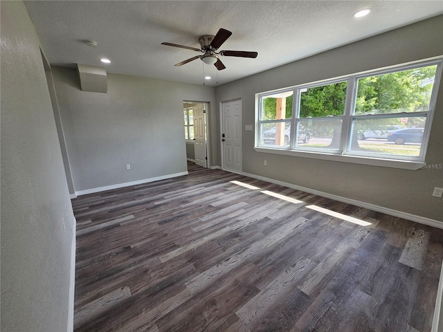 empty room featuring dark wood-style floors, a textured ceiling, and baseboards