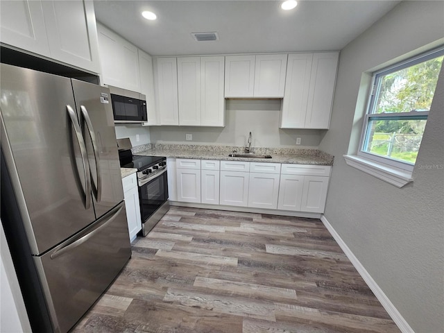 kitchen with a sink, visible vents, appliances with stainless steel finishes, and white cabinetry