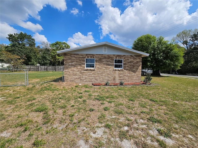 view of property exterior with a yard, brick siding, and fence