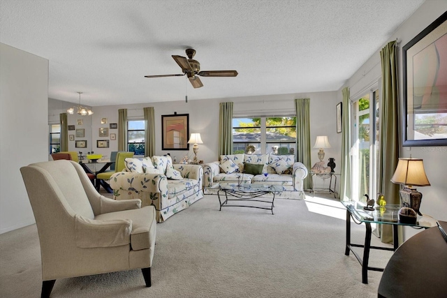 living area featuring carpet flooring, ceiling fan with notable chandelier, and a textured ceiling