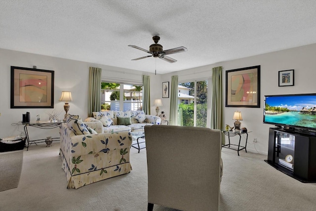 living room with carpet flooring, a ceiling fan, and a textured ceiling