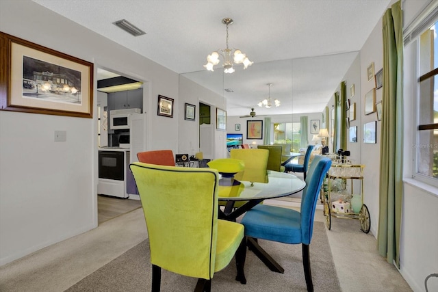 dining room featuring a notable chandelier, visible vents, and light carpet