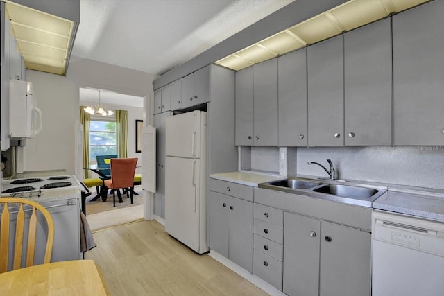 kitchen featuring an inviting chandelier, white appliances, gray cabinets, and a sink