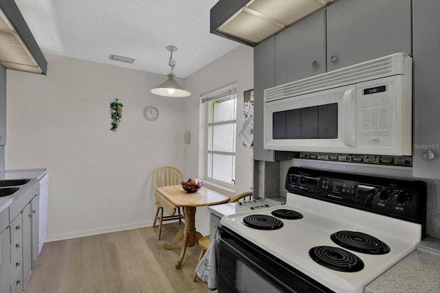 kitchen featuring white appliances, baseboards, visible vents, light wood finished floors, and light countertops