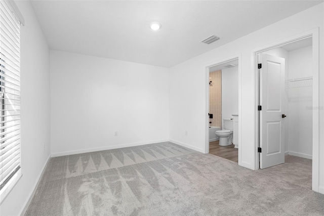 unfurnished bedroom featuring visible vents, multiple windows, a spacious closet, and carpet flooring