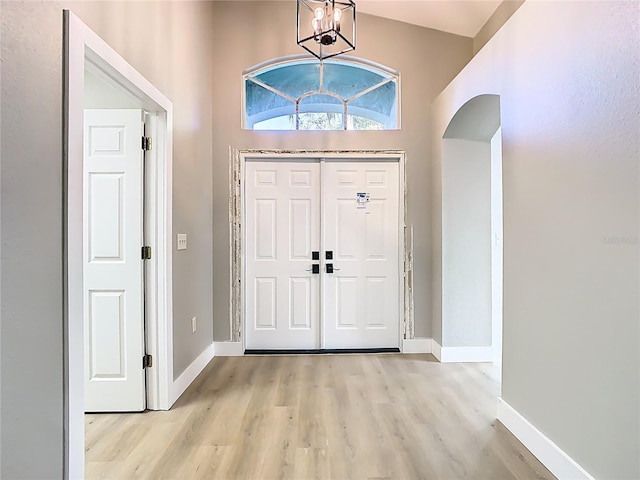 entryway with baseboards, an inviting chandelier, and light wood-style flooring