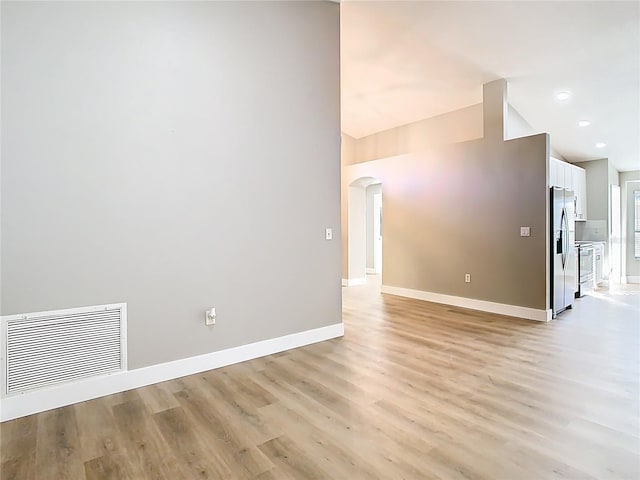 empty room featuring visible vents, recessed lighting, arched walkways, light wood-style floors, and baseboards