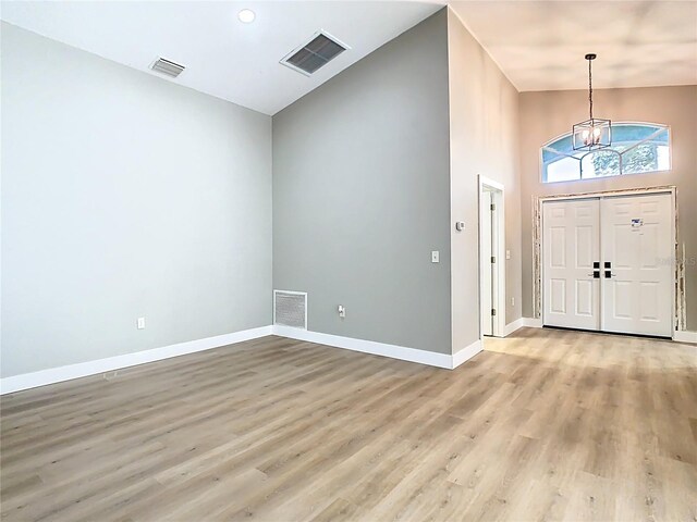 entryway featuring baseboards, light wood-style floors, visible vents, and a chandelier