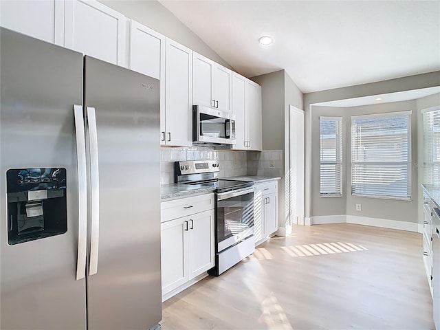 kitchen featuring stainless steel appliances, lofted ceiling, tasteful backsplash, and light wood finished floors