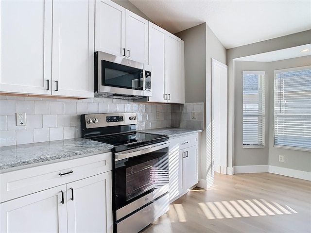 kitchen with tasteful backsplash, white cabinetry, stainless steel appliances, baseboards, and light stone countertops