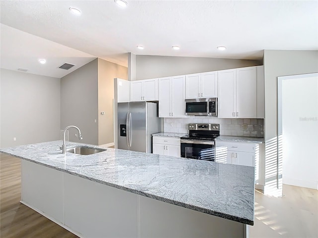 kitchen featuring a sink, vaulted ceiling, appliances with stainless steel finishes, white cabinetry, and light wood-type flooring