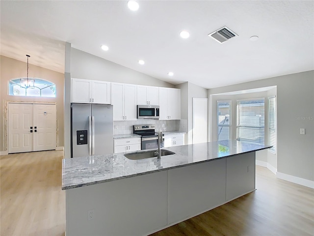 kitchen featuring visible vents, lofted ceiling, appliances with stainless steel finishes, white cabinets, and a sink