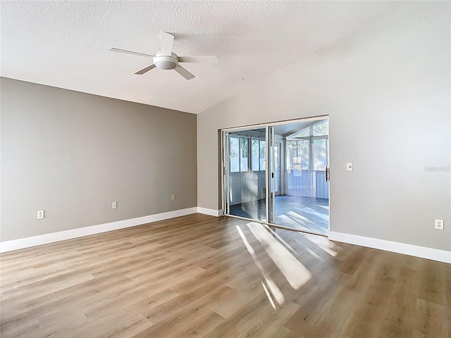 spare room with lofted ceiling, a ceiling fan, a textured ceiling, wood finished floors, and baseboards