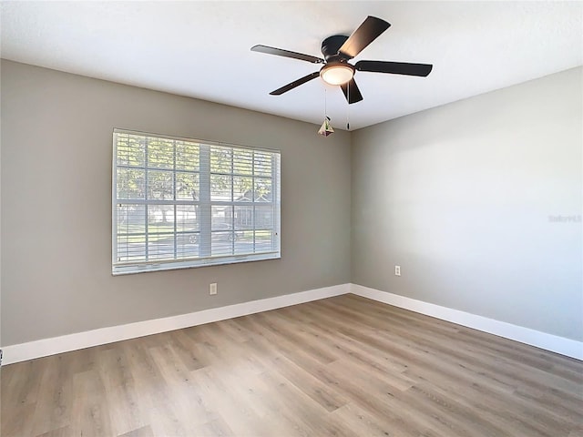 unfurnished room with a ceiling fan, wood finished floors, and baseboards