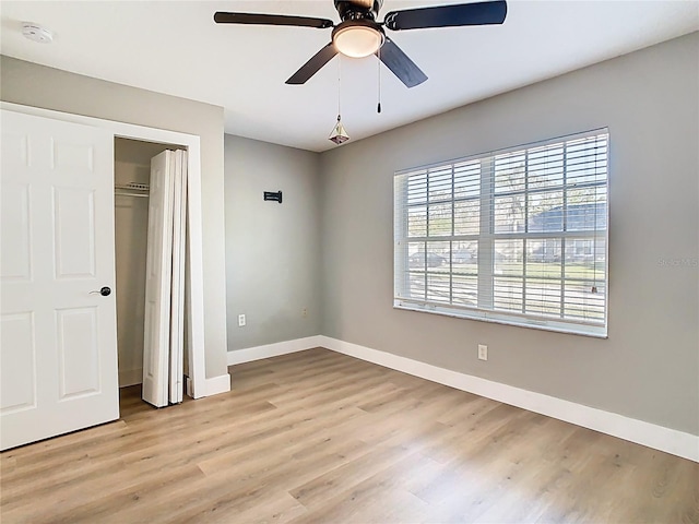 unfurnished bedroom with ceiling fan, a closet, baseboards, and wood finished floors