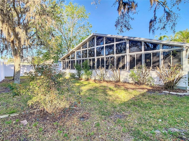 rear view of house featuring a yard, fence, and a sunroom