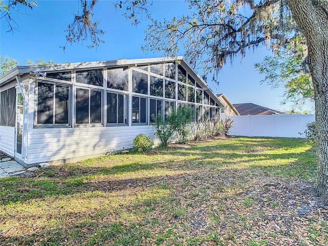 view of home's exterior with fence, a yard, and a sunroom