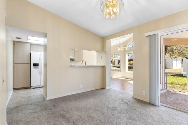 interior space featuring visible vents, light carpet, ceiling fan with notable chandelier, light tile patterned flooring, and lofted ceiling