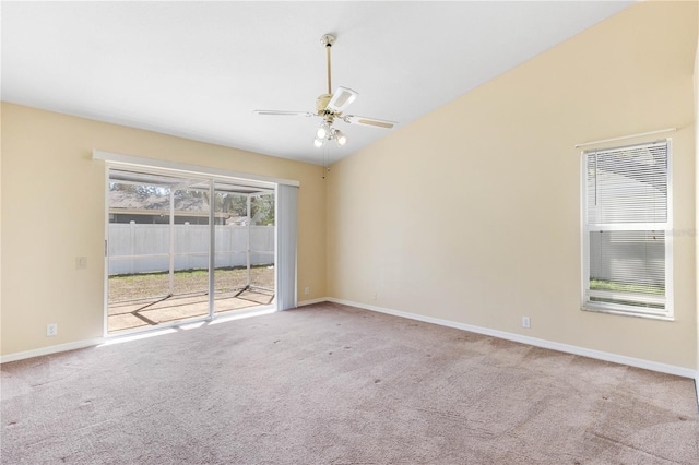 carpeted spare room with vaulted ceiling, a ceiling fan, and baseboards