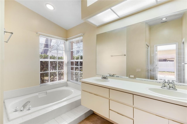 bathroom with a sink, lofted ceiling, a bath, and double vanity