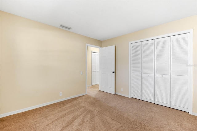 unfurnished bedroom featuring baseboards, visible vents, a closet, and light carpet